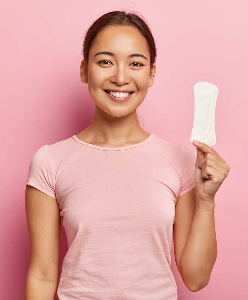 A girl in pink t-shirt holding plain white hydrophilic non woven sanitary pad in her hand