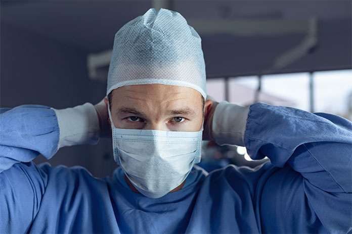 A doctor is wearing blue non woven medical products such as non-woven gown, cap and mask